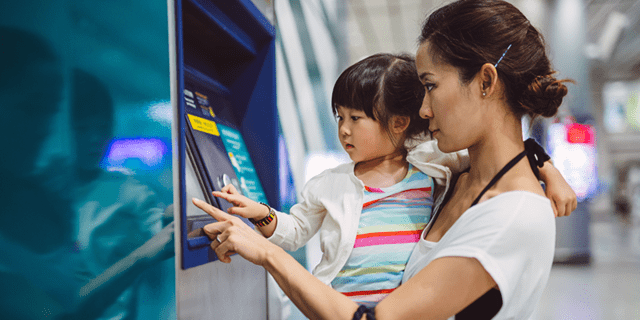 Women using ATM while carrying baby